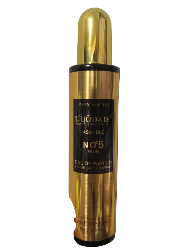 Gold and black perfume bottle held by a hand against a plain background